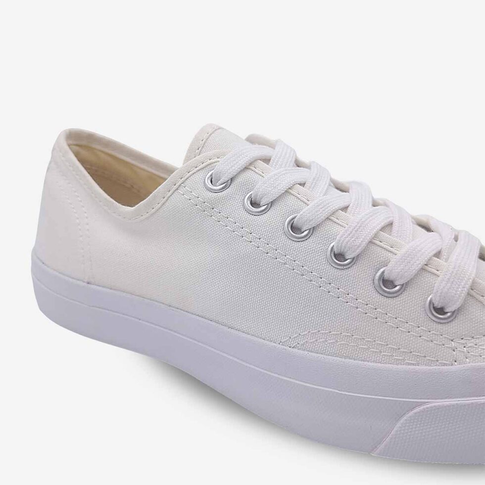 Close-up of Jack Purcell low white canvas sneaker with blue sole and lace-up closure