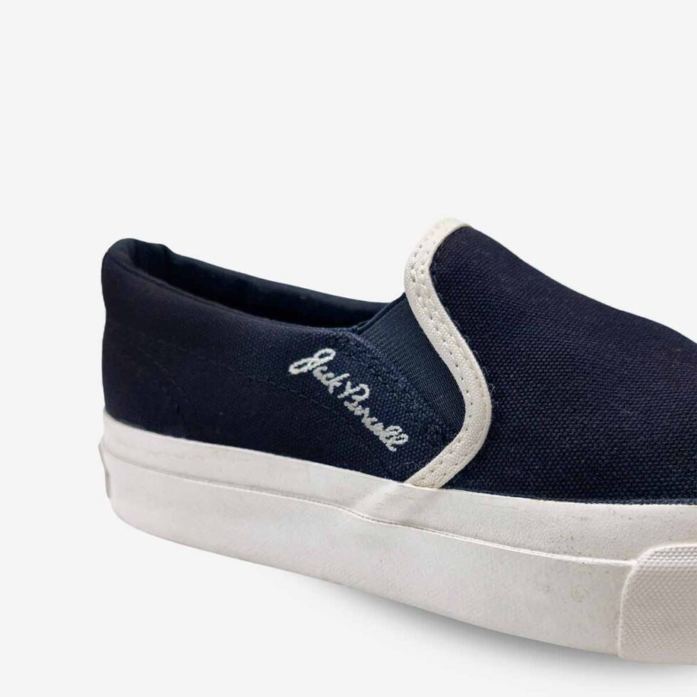 Close-up of Jack Purcell youth slip-on sneaker in black canvas with signature Brand detail