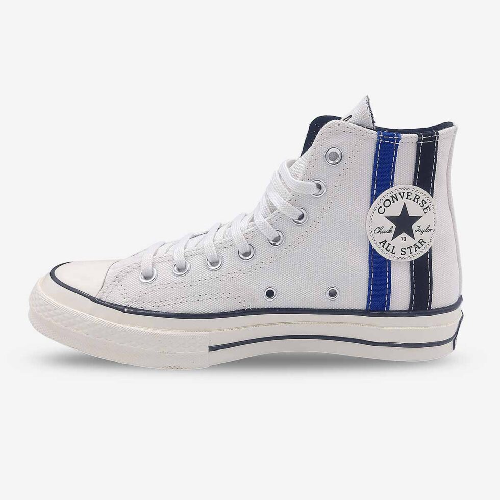 Inner side view of Converse Chuck 70 high-tops in vintage white showing Chuck Taylor branding on tongue and black & blue ankle stripes.