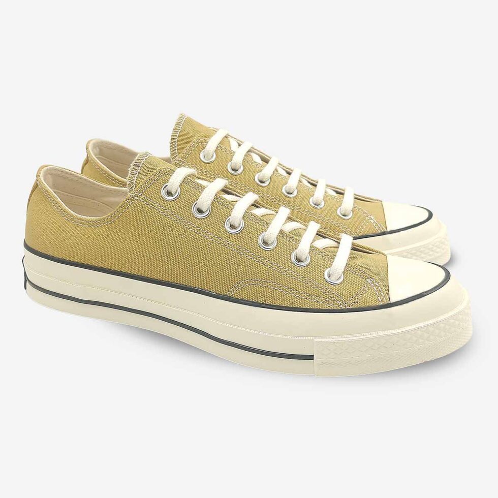 Angled pair of Converse Chuck 70 Low sneakers in a light khaki colour.