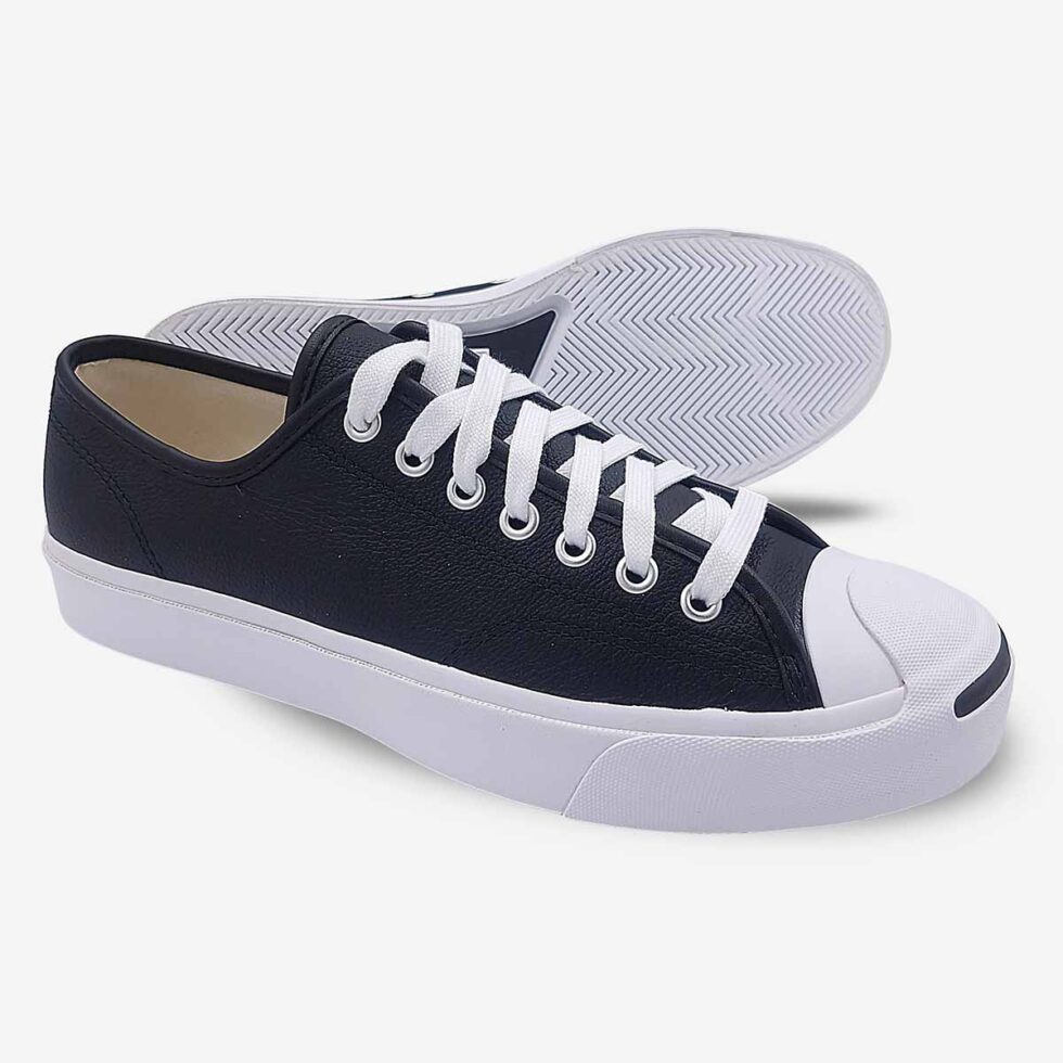 Side-bottom angle of Jack Purcell low black leather sneakers showing white rubber outsole